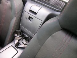 Bagerst mellem sæderne er der kopholdere og et aflåselige rum. Grebet øverst i billedet udløser kalechen, som kan lukke bilen få sekunder senere, - og med en hånd.